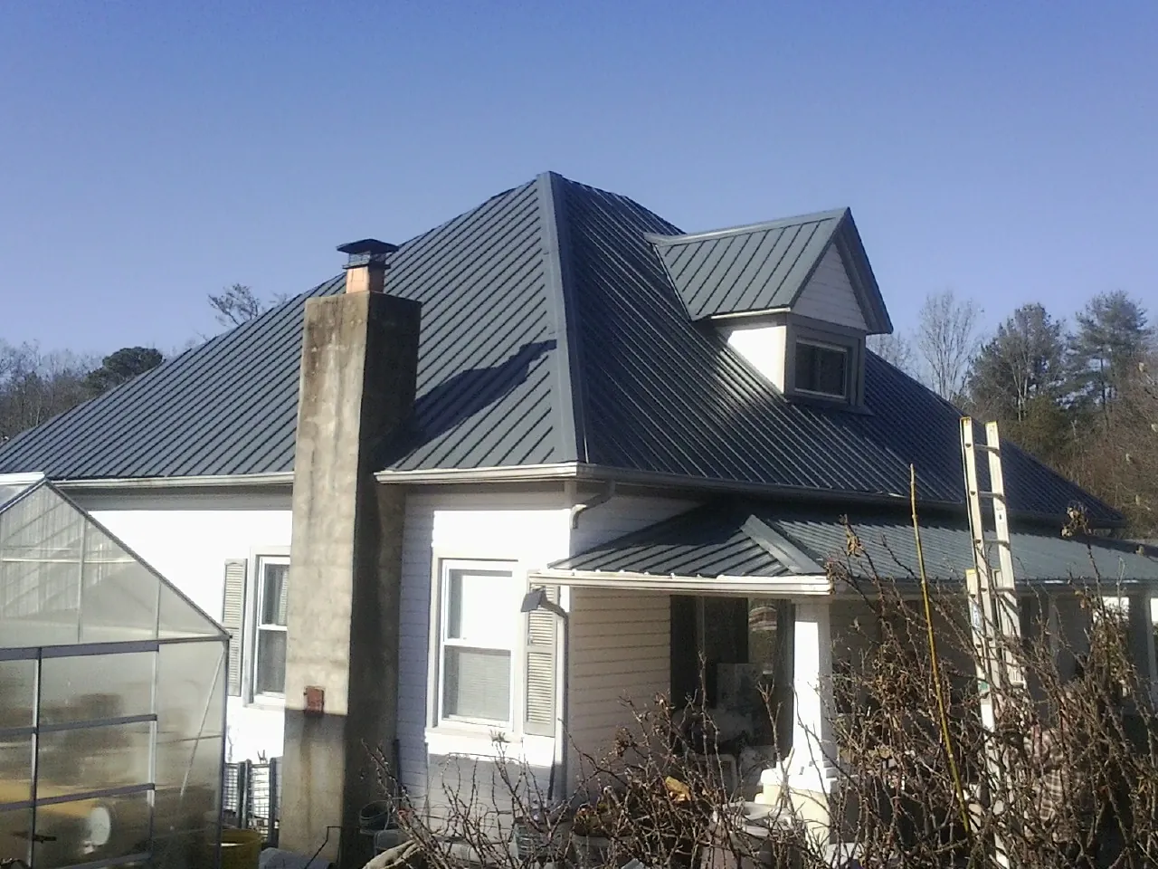 Dark blue standing seam metal roof on a white farmhouse with dormer — Slate & Tile Roof Repair by Roofing Brothers in Deep River