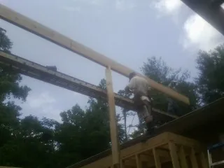 Carpenter setting a ridge beam over a new addition frame — Ice Dam Removal by Roofing Brothers in Deep River