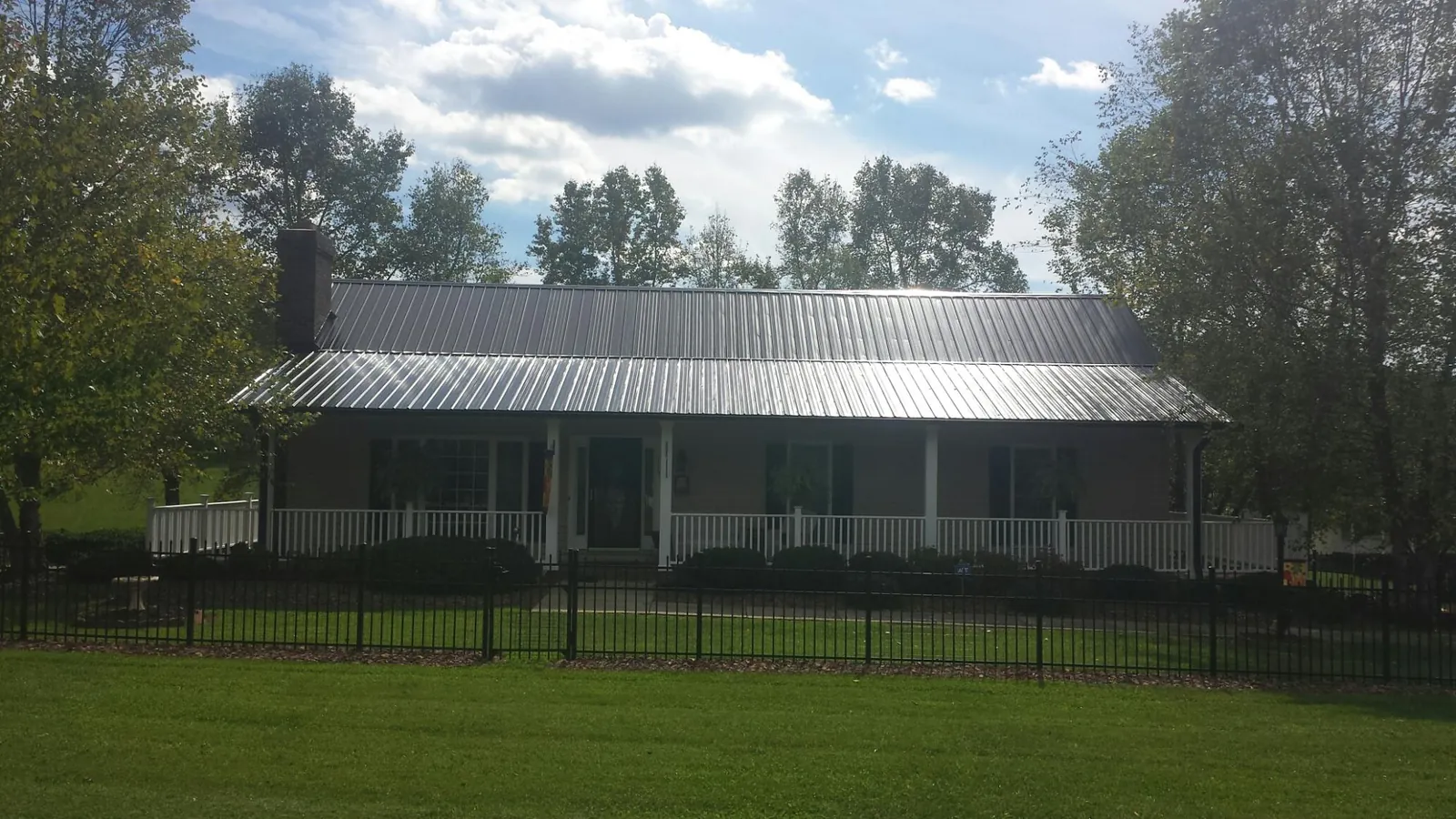 Gray metal roof on a brick ranch with a full width front porch — Gutter Guard Installation work by our crew in Deep River